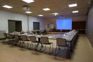 a conference room with tables and chairs and a screen at Hôtel Restaurant Ar Milin-Logis hôtels in Châteaubourg
