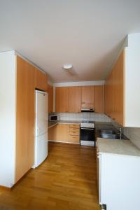 a kitchen with wooden cabinets and a white refrigerator at LibO-apartment, Rypys 74 X in Kuopio