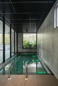 a pool with green water in a room with windows at Apto Moderno no Coração da Cidade - CA802 in Maringá