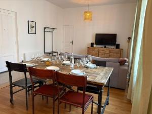 a dining room table with wine glasses and a couch at Larbaud 6 - Hypercentre - Proche Thermes - Spacieux in Vichy