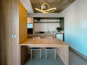 a kitchen with a wooden table and some chairs at Apto Moderno no Coração da Cidade - CA802 in Maringá