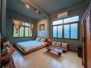 a bedroom with a bed and a table and windows at Sita Home in Danang