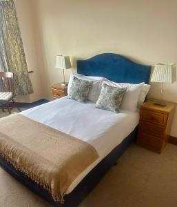 a bedroom with a large bed with a blue headboard at Seashore Lodge Guesthouse in Galway +2 photos