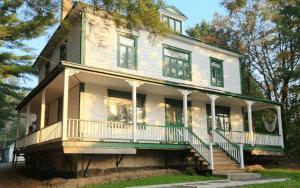 a large white house with a porch and stairs at Auberge des Korrigans in Stoneham +17 photos