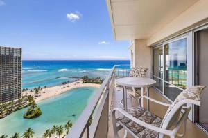 a balcony with a table and chairs and a view of the beach at #Marbella Lane - Luxe 2BR with Panoramic Ocean View in Honolulu