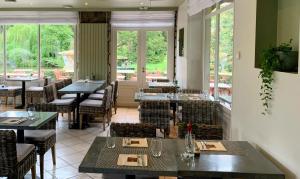 a restaurant with tables and chairs and windows at Hôtel Restaurant Ar Milin-Logis hôtels in Châteaubourg