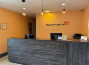 an office lobby with a large counter with atranswegianit sign at Transamerica Fit Contagem in Contagem