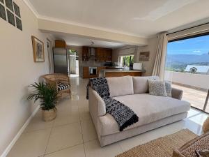 a living room with a couch and a kitchen at Spacious sunny secure and central with scenic views in Hout Bay