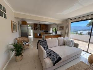 a living room with a couch and a kitchen at Spacious sunny secure and central with scenic views in Hout Bay
