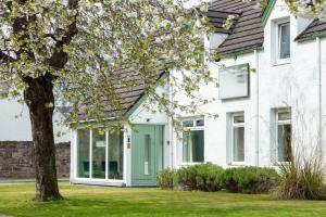 a white house with a green door and a tree at The Ullapool Rooms in Ullapool