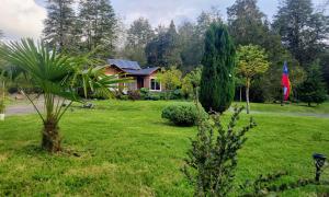 a house in a yard with a green lawn at Cabañas Los Volcanes Ensenada Puerto Varas in La Ensenada