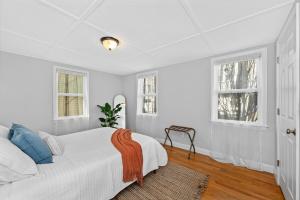 a white bedroom with a bed and two windows at Boston Condo With FREE Parking in Boston