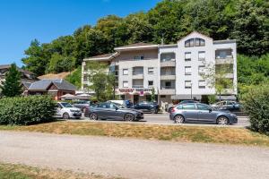 a parking lot with cars parked in front of a building at le Thermal 108 in Saint-Martin-d'Uriage