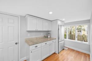 a white kitchen with white cabinets and a window at Boston Condo With FREE Parking in Boston