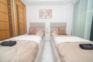 two beds in a room with white walls at Luxury Abraj YK 120m2 in Tangier
