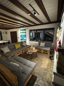 a living room with couches and tables and windows at Cabana Gala Doftanei in Trăisteni