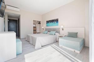 a white bedroom with a bed and a chair at azuLine Hotel Llevant in San Antonio +13 photos