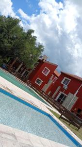 a red building and a swimming pool in front of a building at Alma Apart in Los Molles
