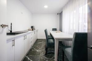 a kitchen with white cabinets and a table and chairs at Căsuța din Vale in Voronet