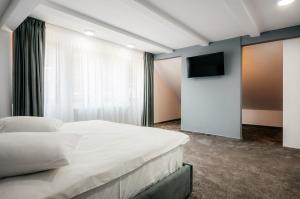 a bedroom with a white bed and a flat screen tv at Căsuța din Vale in Voronet