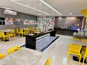 a restaurant with yellow chairs and tables and a counter at Hotel Avalon Maringá Econômico in Maringá