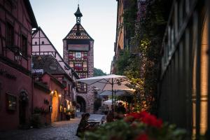 a group of people sitting under an umbrella on a street at Le B. Suites, Chambres & Restaurant in Riquewihr
