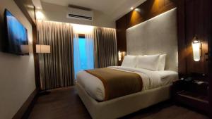a hotel room with a large bed and a window at Hotel Poonja International in Mangalore +90 photos
