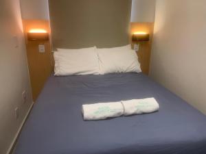 a bed in a small room with a towel on it at Hostel Mirandopólis in São Paulo