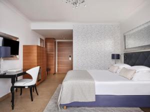 a bedroom with a large bed and a desk at Amadria Park Hotel Royal in Opatija