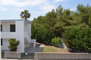 a white building with a staircase next to trees at Mya Vacanze in Torre dell'Orso