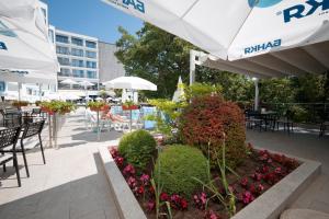 a patio with tables and chairs with flowers and umbrellas at Hotel Slavey - All Inclusive in Golden Sands