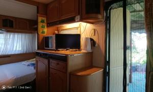a small kitchen with a tv and a bed in an rv at Граничар 3 СЪРФА - морската каюта in Granichar