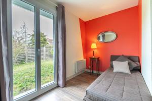 a bedroom with an orange wall with a bed and a window at La Belle Escale - Maison proche gare et d'Orléans in Fleury-les-Aubrais