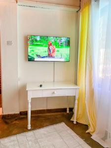 a white desk with a television on a wall at Palm Villa at Villa Sol in Mombasa