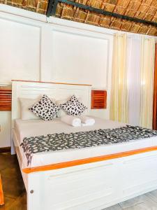 a white bed with black and white pillows on it at Palm Villa at Villa Sol in Mombasa +17 photos