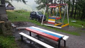 a park with a bench and a swing and a car at Chata Katarina in Lipany