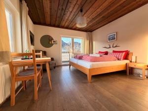 a bedroom with a bed with red pillows and a desk at Boutique Hotel Alpenhof in Sankt Martin am Tennengebirge