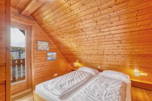 a bed in a wooden room with a window at Seepark-Lodge in Kirchheim