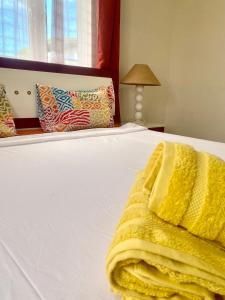 a white bed with a yellow blanket on it at Appartement first floor in Trou aux Biches