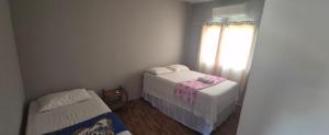 a small bedroom with two beds and a window at Pousada Cactos in Chapada dos Guimarães