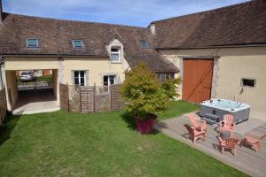 a backyard with a table and chairs and a grill at Au logis de Bayard in Vareilles