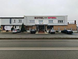a hotel entrance with cars parked in a parking lot at Hotel Riviera in Mierzyn