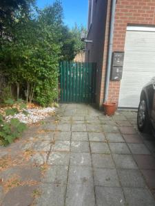 a driveway in front of a house with a green gate at Studio confortable situé à Woluwe Saint Lambert in Brussels