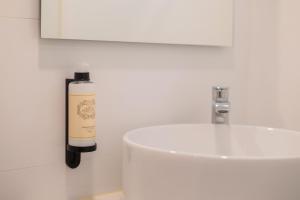 a white bathroom with a bottle of soap next to a sink at Uma Poveiros in Porto +43 photos