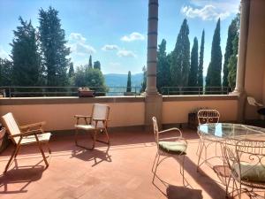a balcony with chairs and a glass table and a view at Casa per la Pace in Impruneta