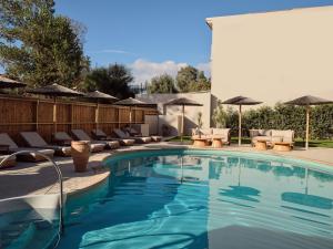 a swimming pool with lounge chairs and umbrellas at Nemesis Aparthotel in Laganas