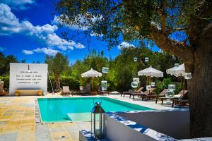 a swimming pool with a sign next to a tree at Case Fra Gli Ulivi in Spongano