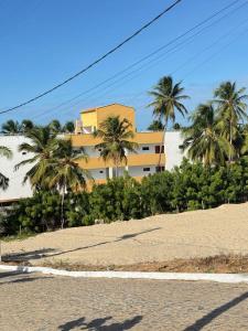 a building on a beach with palm trees in the background at Via do Sol flats in Amontada