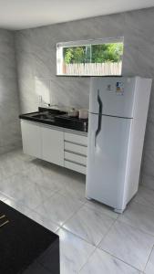 a kitchen with a white refrigerator and a window at Via do Sol flats in Amontada