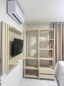 a bedroom with a book shelf and a tv at Via do Sol flats in Amontada